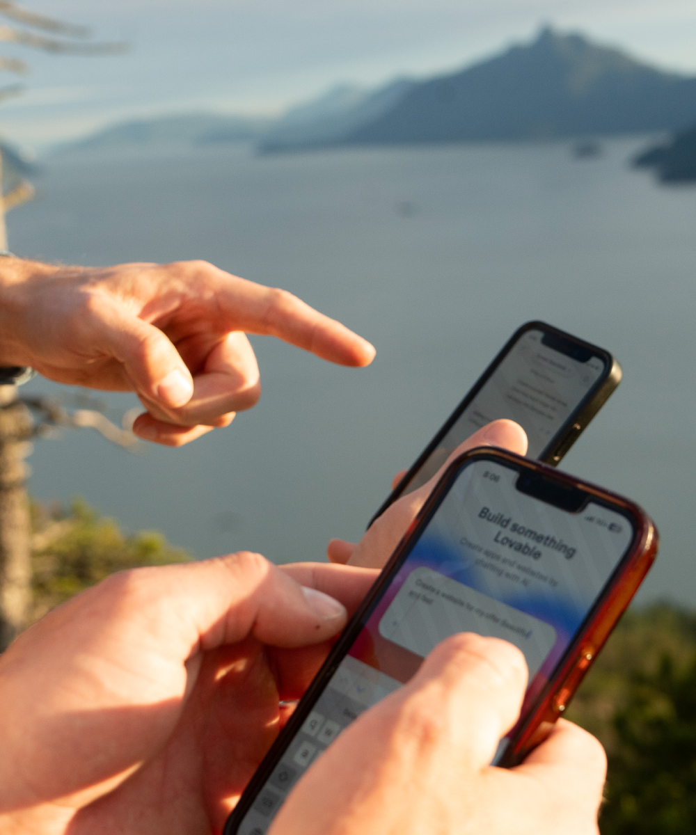 Nik and Rai building on their phones overlooking the ocean